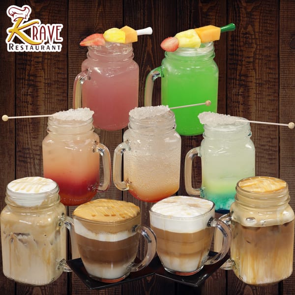 Assortment of colorful Krave Restaurant drinks, including iced coffees, sodas, and fruit juices in mason jars.