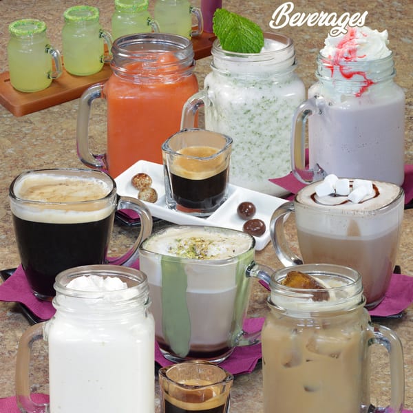 Assortment of beverages, including iced coffee, hot chocolate, smoothies, and lemonades, on a textured surface.