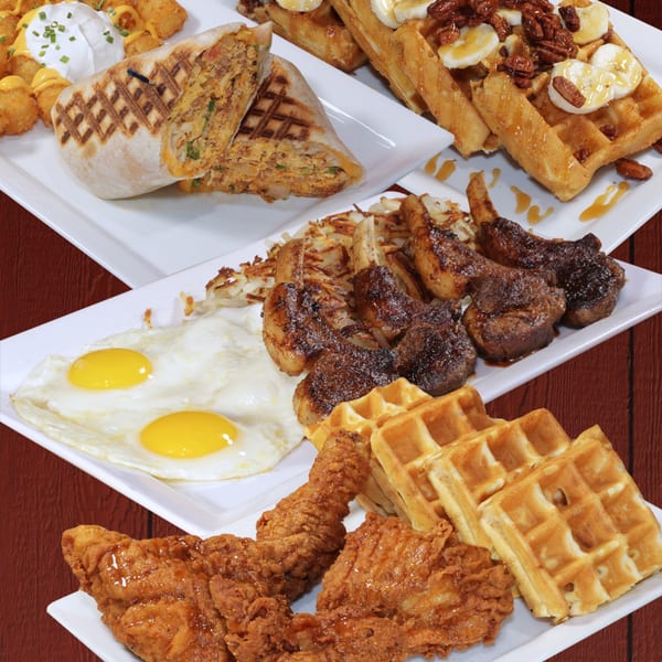 Plates of breakfast food including a burrito, waffles with bananas, fried eggs, and chicken.
