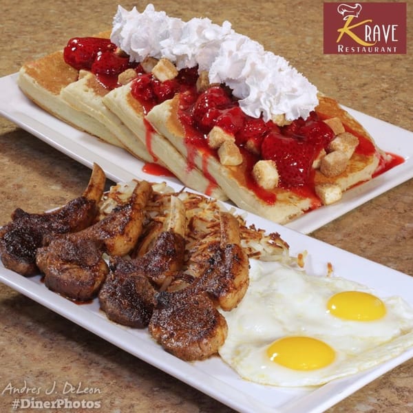 Krave Restaurant's breakfast with pancakes, strawberries, whipped cream, lamb chops, hash browns, and fried eggs.
