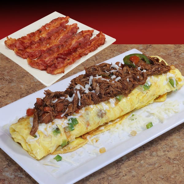 A breakfast plate with a large omelet topped with shredded beef and cheese, and a side of bacon.