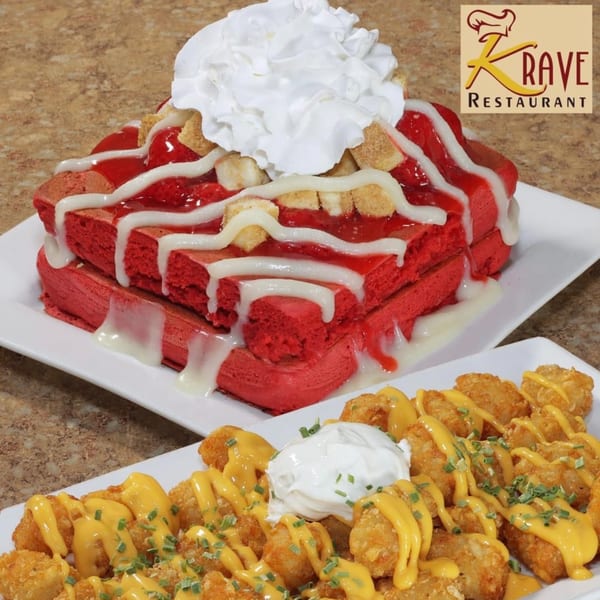 Red velvet waffles with whipped cream and strawberry topping, alongside tater tots with cheese sauce and sour cream.